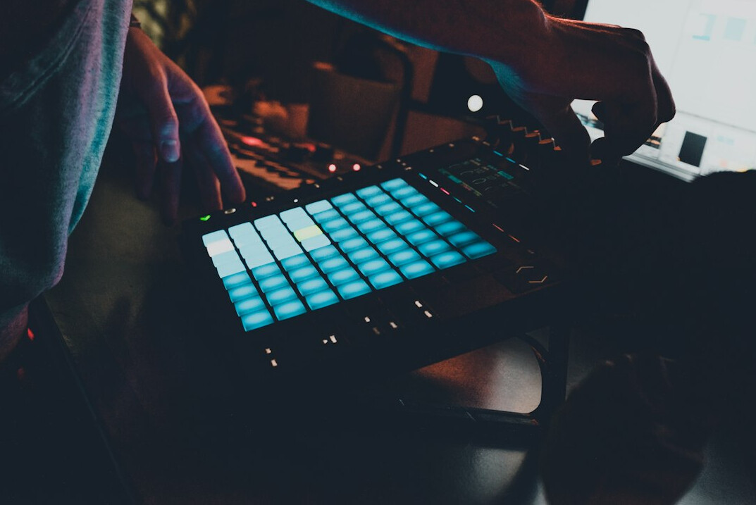 Hands operating a vision mixer switcher panel with illuminated buttons